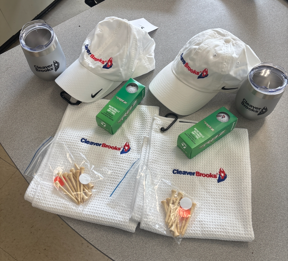 (1 of 2) CleaverBrooks Golf Package For Two - Includes 12 oz Starlight Traveller Mug, Golf Towels, Nike Hats, TaylorMade Golf Balls, Tees & Ball Markers